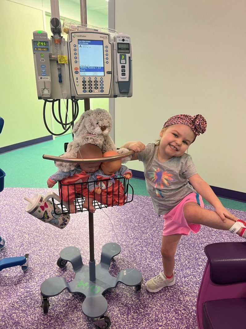 Bryleigh posing with her dolls on the monitoring pole