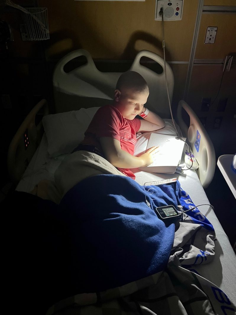 Max reading at night in his hospital bed with a reading light
