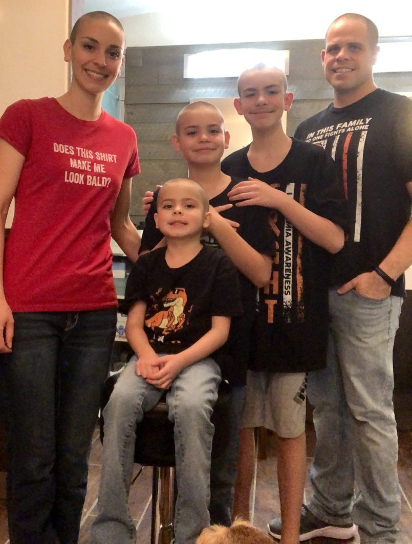 Era and family posing with shaved heads for cancer awareness